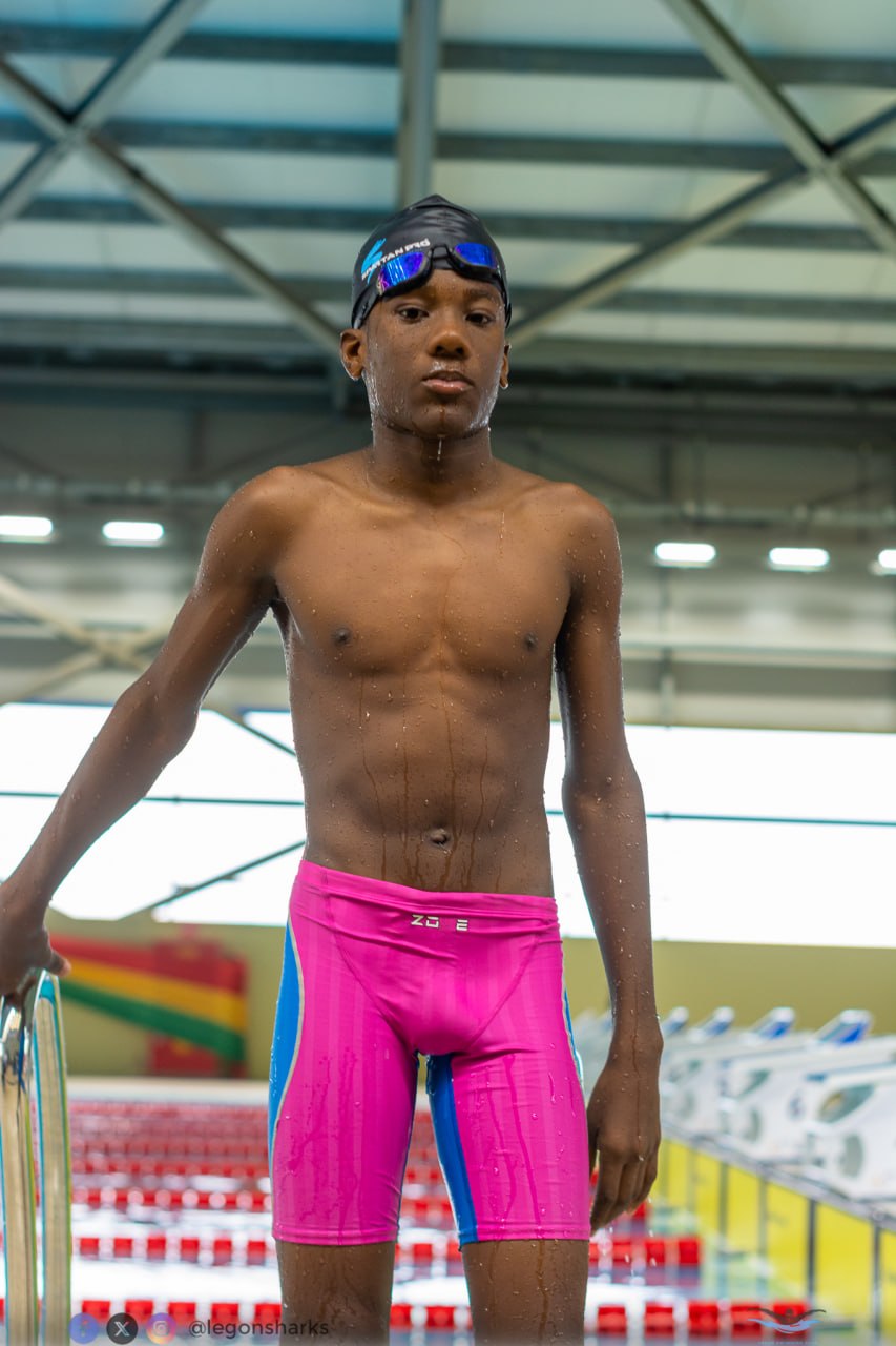 Young male swimmer in pink blue Zone3 jammers poolside pre-race