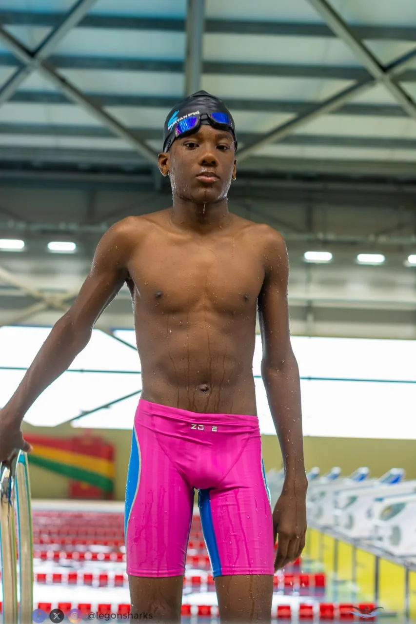 Young male swimmer in pink blue Zone3 jammers poolside pre-race