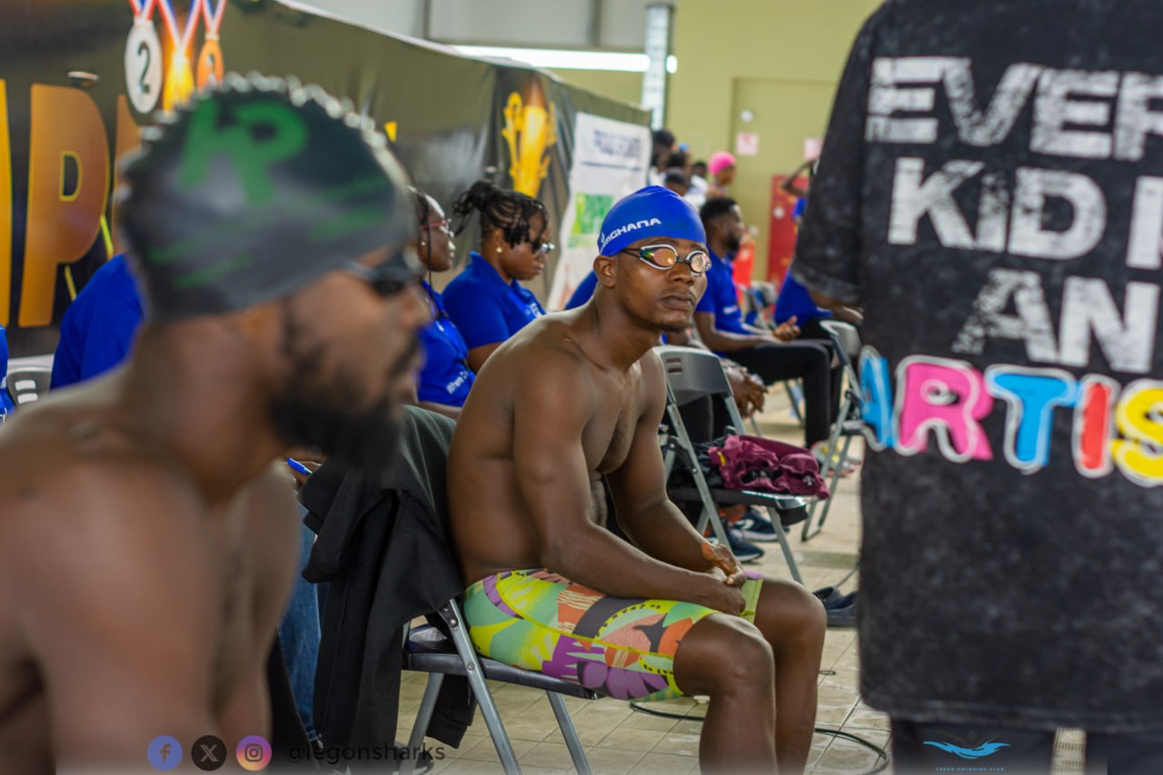Adult male swimmer in Ghana cap waiting poolside Legon Sharks shirt