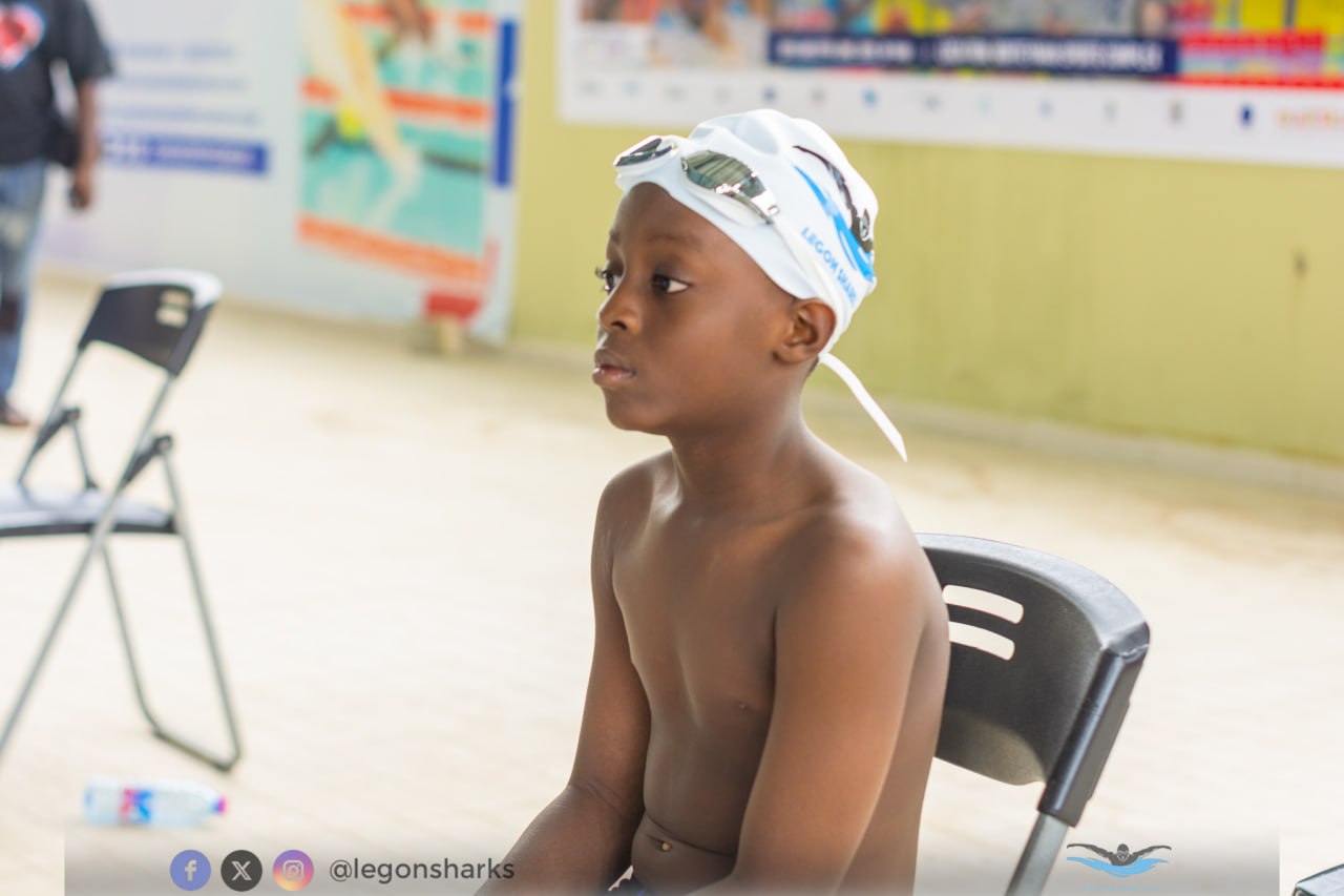 Young boy in oversized Legon Sharks cap watching competition