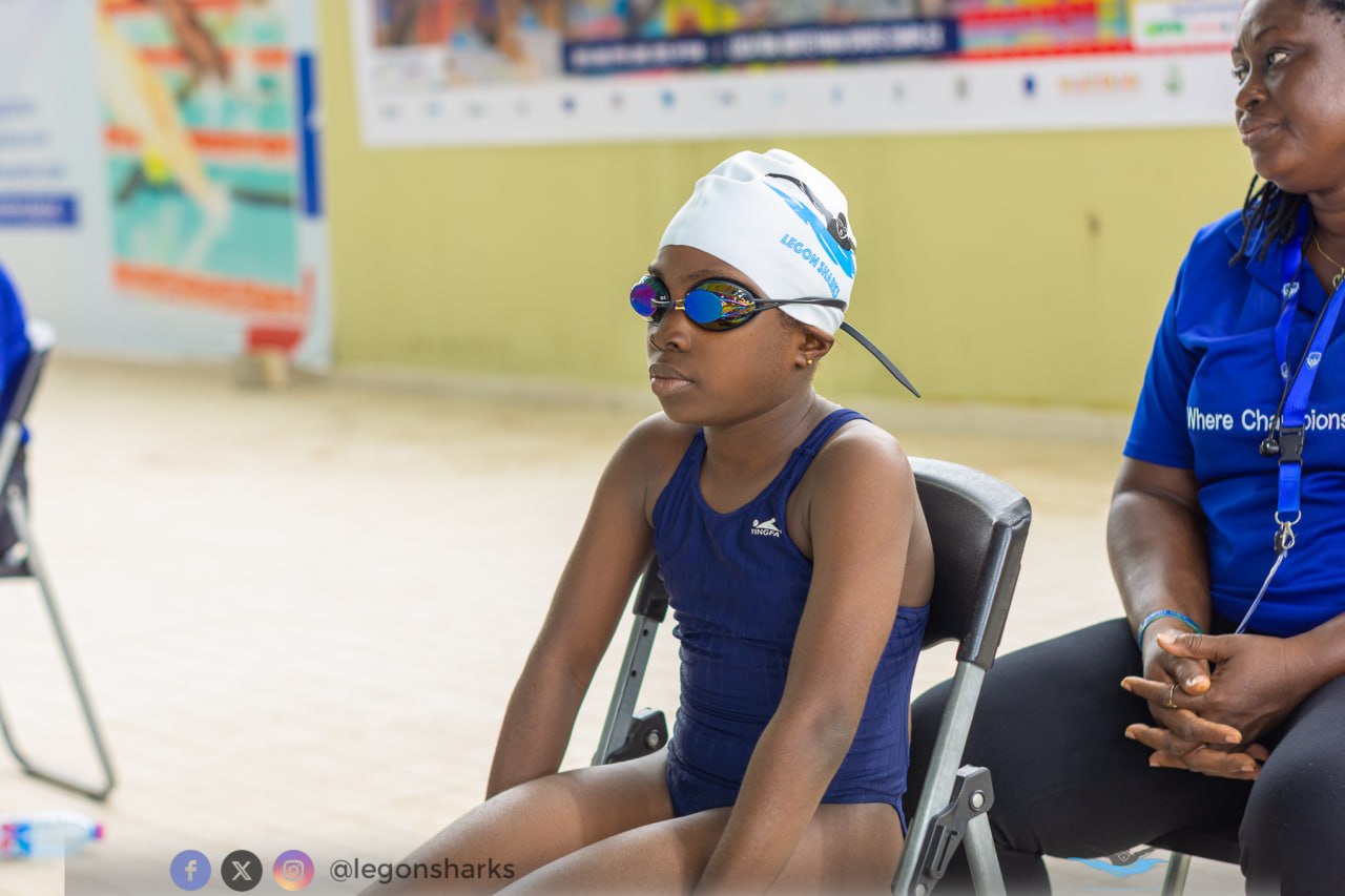 Young girl in navy Yingfa suit Legon Sharks cap goggles waiting