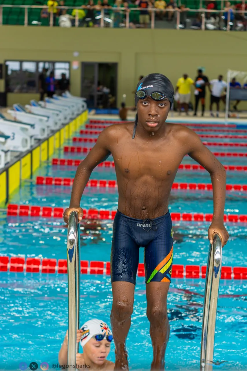 Teenage male swimmer climbing out of pool Arena jammers Ghana colors