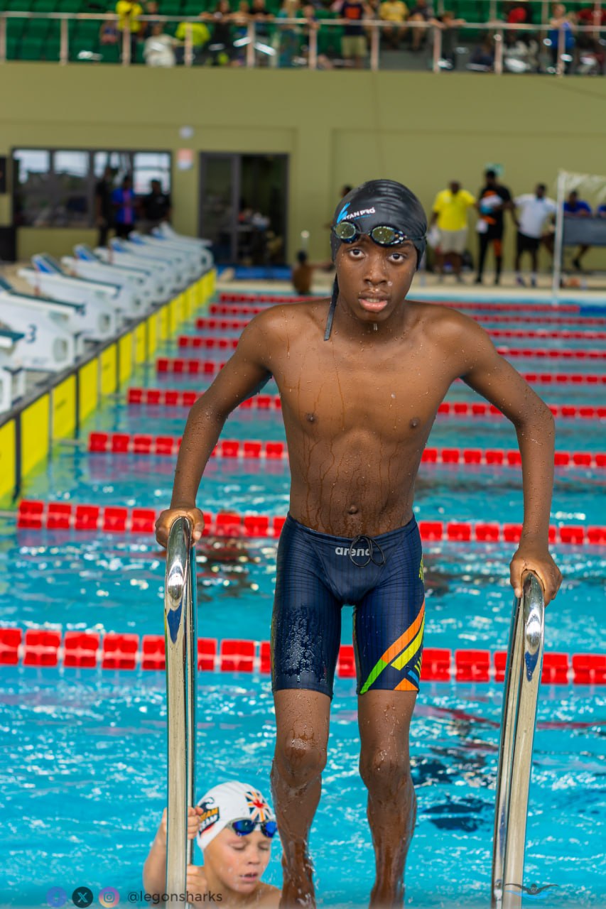 Teenage male swimmer climbing out of pool