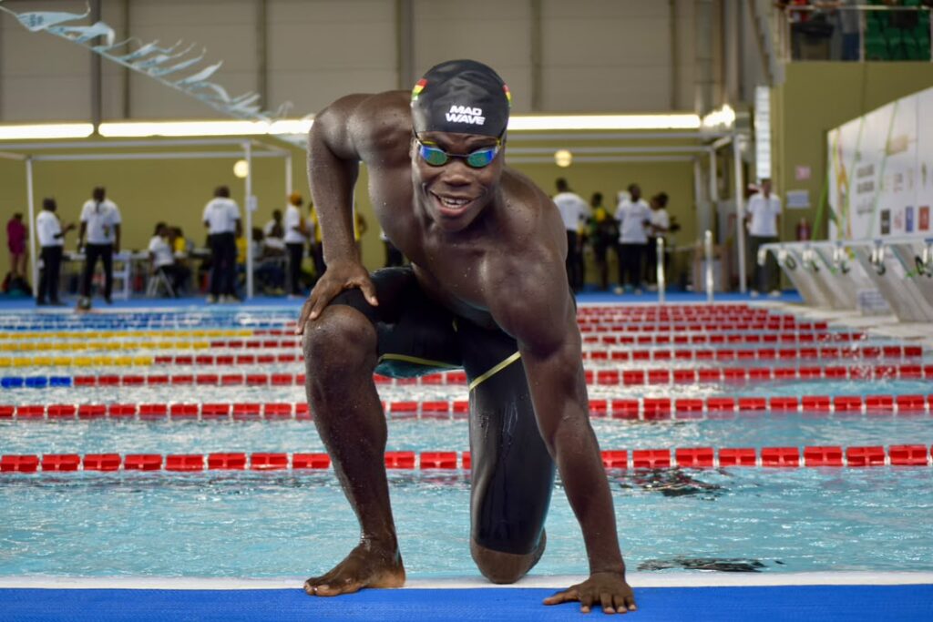 Christian Nii Nortey crouched at the starting block of an indoor competition pool