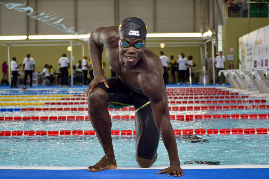 Christian Nii Nortey crouched at the starting block of an indoor competition pool